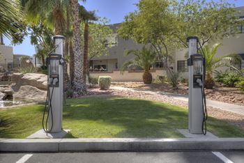 Two gas pumps in a parking lot in front of a house